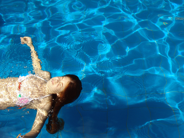 děvče plave v bazéně za slunečného dne